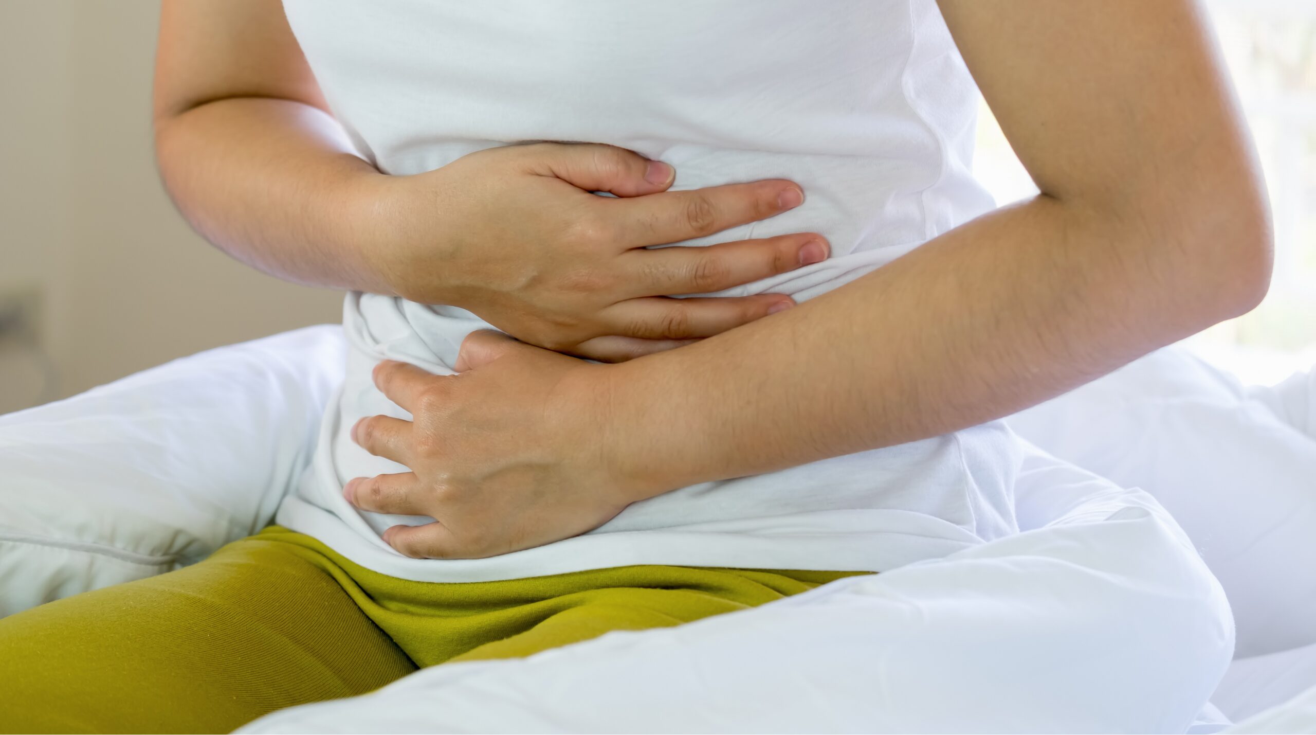 お腹を押さえて痛みに耐える女性